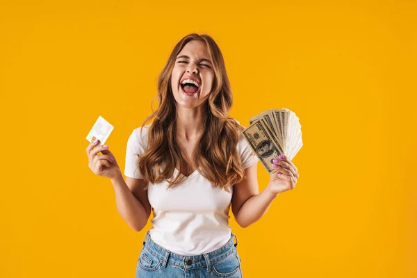 Foto einer entzückten Frau, die sich freut, während sie Dollargeld und Kreditkarte in der Hand hält — Stockfoto