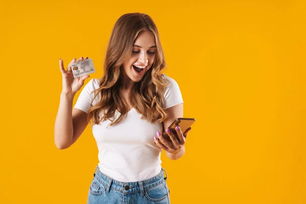 Foto van verbaasd jonge vrouw blijdschap terwijl het houden van creditcard en smartphone — Stockfoto