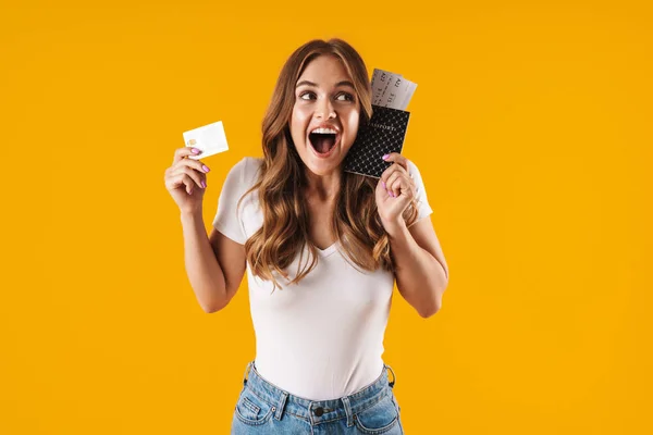 Photo of surprised young woman rejoicing while holding credit card and passport with travel tickets — Stock Photo, Image