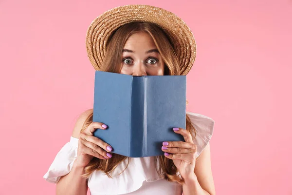 Aranyos fiatal csinos nő pózol elszigetelt rózsaszín fal háttér könyv. — Stock Fotó
