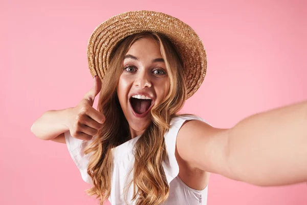 Felice sorpreso giovane bella donna posa isolato su sfondo rosa muro mostrando pollici in su gesto prendere un selfie dalla fotocamera . — Foto Stock