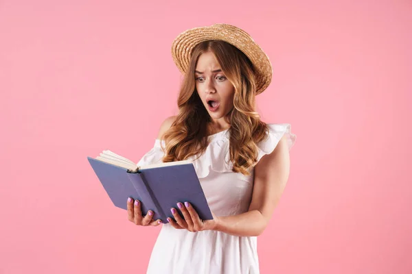 Döbbenten zavaros csinos fiatal csinos nő jelentő elszigetelt több mint rózsaszín fal háttérben olvasás könyv. — Stock Fotó
