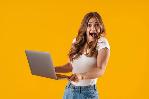 Immagine di una donna caucasica sorpresa che indossa una t-shirt di base esprimendo gioia mentre tiene in mano il computer portatile — Foto Stock