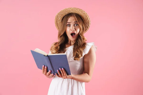 Σοκαρισμένος μπερδεμένος χαριτωμένο νεαρή όμορφη γυναίκα που παρουσιάζουν απομονωμένη πάνω από ροζ τοίχο φόντο διαβάζοντας βιβλίο. — Φωτογραφία Αρχείου