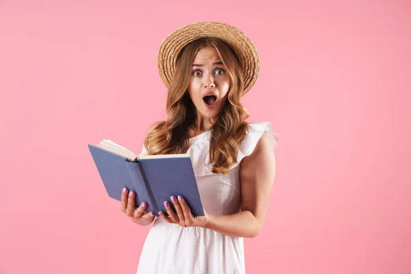 Geschokt verward leuke jonge mooie vrouw poseren geïsoleerd over roze muur achtergrond lezen boek. — Stockfoto