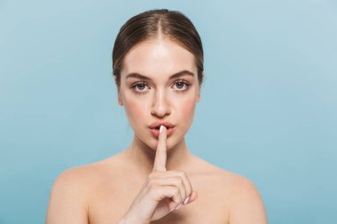 Mavi duvar arka plan üzerinde izole poz Pretty genç kadın sessizlik jest yapmak.