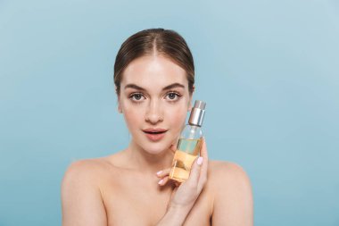 Pretty genç kadın yağ losyonu tutan mavi duvar arka plan üzerinde izole poz.