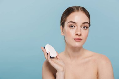 Mavi duvar arka plan üzerinde izole poz Amazing genç kadın krem ile cildine dikkat çekmek.