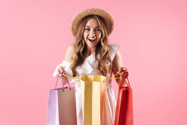 Imagem de mulher caucasiana espantada vestindo chapéu de palha perguntando e segurando sacos de compras — Fotografia de Stock