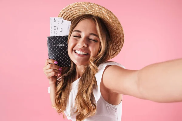 Junge hübsche Frau posiert isoliert über rosa Wand Hintergrund mit Pass mit Tickets machen ein Selfie mit der Kamera. — Stockfoto
