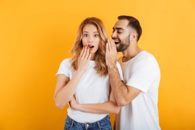 Birbirlerine sırları fısıldayan ya da dedikodular fısıldayan temel t-shirt sürpriz çift erkek ve kadın Görüntü