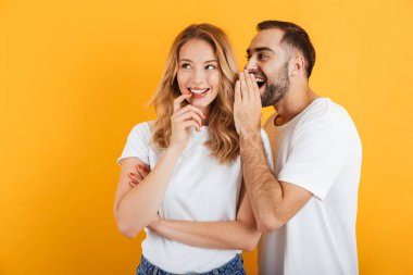 Mutlu çift erkek ve kadın temel t-shirt sırları fısıldıyor veya birbirlerine dedikodu görüntü