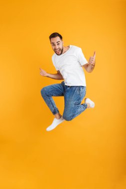 Yakışıklı beyaz adam sakallı atlama ve başparmak gösteren tam uzunlukta fotoğraf