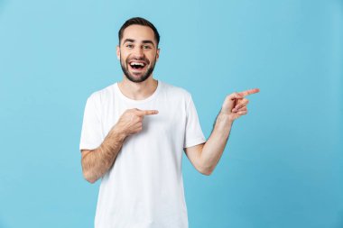 Duygusal genç mutlu sakallı adam copyspace işaret mavi duvar arka plan üzerinde izole poz.