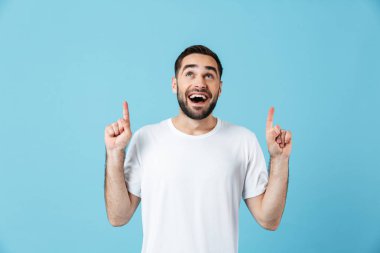Heyecanlı genç mutlu sakallı adam copyspace işaret mavi duvar arka plan üzerinde izole poz.