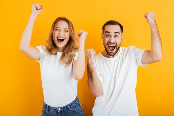 Porträt eines überraschten zufriedenen Paares in einfachen T-Shirts jubelnd und mit geballten Fäusten — Stockfoto