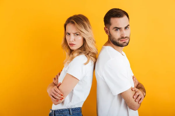 Bild eines verwirrten Paares in einfachen T-Shirts, das während des Kampfes Rücken an Rücken steht und die Stirn runzelt — Stockfoto