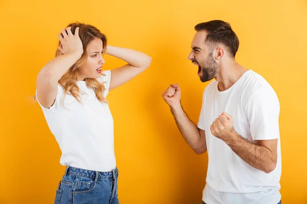 戦いの最中にお互いに叫び合うベーシックなTシャツを着た怒りのカップルの男女のイメージ — ストック写真