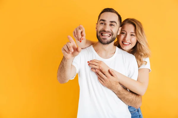 Beeld van mooie paar man en vrouw uiten wonder terwijl wijzende vingers opzij bij copyspace — Stockfoto