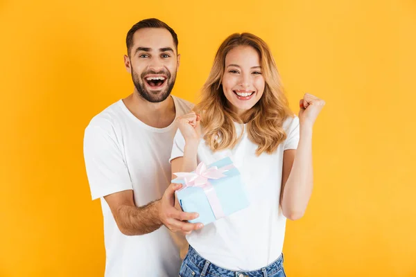 Bild eines lächelnden Paares, das sich freut, während ein schöner Mann der schönen Frau eine Schachtel schenkt — Stockfoto