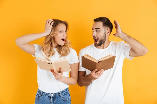 Imagem do casal impressionado homem e mulher expressando maravilha ao ler livros juntos — Fotografia de Stock