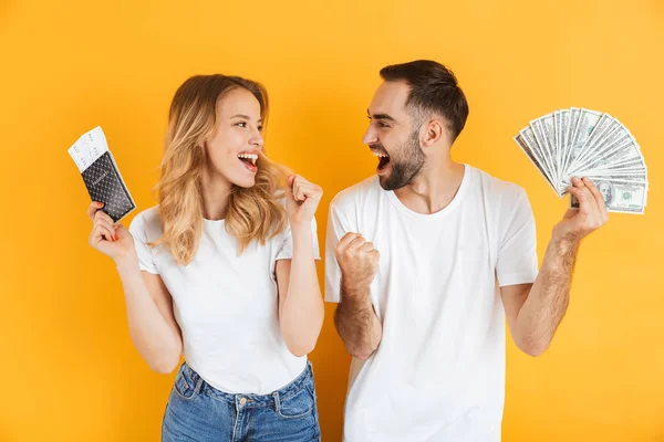 Bild eines fröhlichen Paares, das sich freut, während es Bargeld und Reisepass mit Reisetickets in der Hand hält — Stockfoto