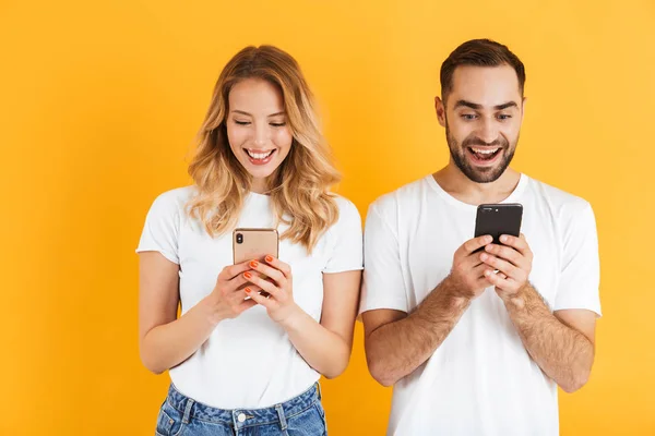 Изображение красивой пары мужчины и женщины, улыбающихся, держа мобильники вместе — стоковое фото
