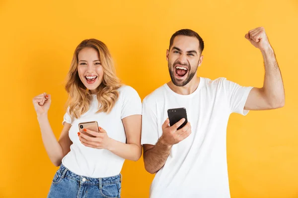 Imagen de pareja excitada hombre y mujer apretando puños mientras mantienen juntos los teléfonos celulares — Foto de Stock