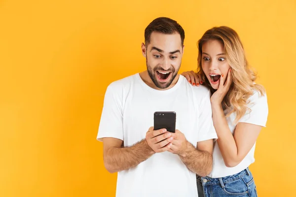 Изображение изумленной пары мужчин и женщин, удивляющихся, глядя на мобильный телефон вместе — стоковое фото