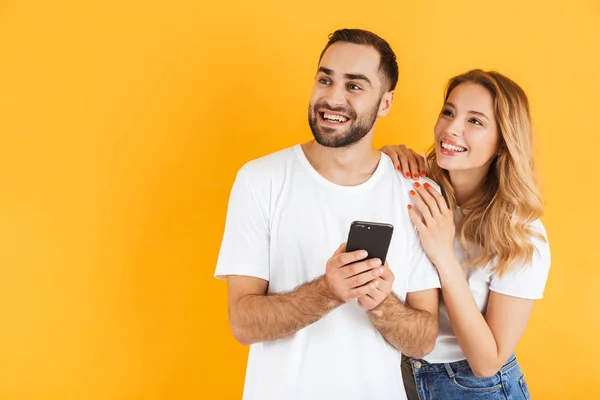 Obraz spokojených mužů a žen, kteří se usmívají a používají mobilní telefon, zatímco se dívají stranou na copyspace — Stock fotografie