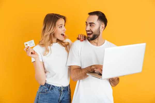 Obraz pięknej pary mężczyzny i kobiety, wyrażając niespodziankę razem trzymając laptopa i karty kredytowej — Zdjęcie stockowe