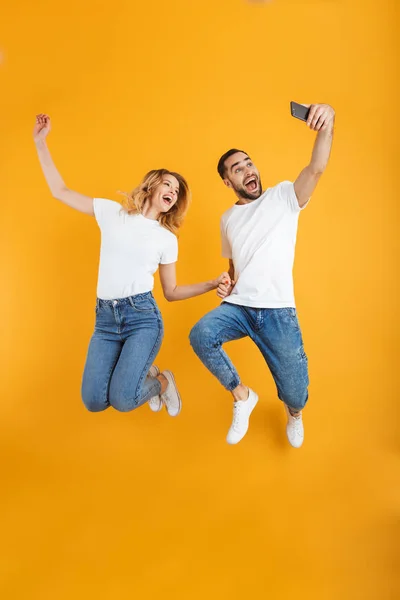 In voller Länge Bild von fröhlichen Paar jubelt und springt, während Selfie-Foto auf dem Handy — Stockfoto