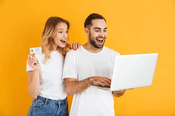 Wizerunek szczęśliwego Para mężczyzna i kobieta wyrażając niespodziankę razem trzymając laptopa i karty kredytowej — Zdjęcie stockowe