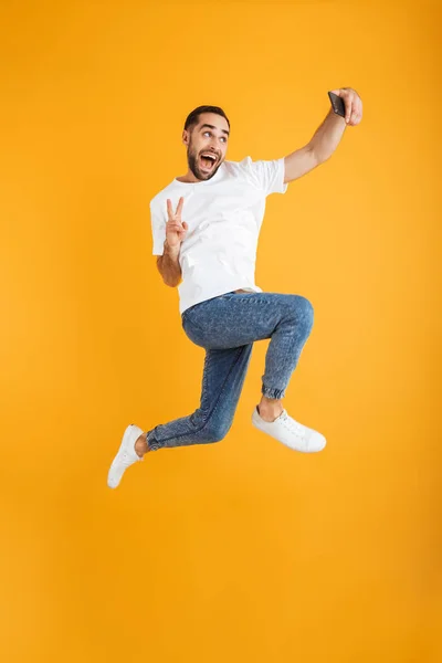 Full length foto di felice uomo caucasico avendo barba prendere selfie sul cellulare e mostrando segno di pace — Foto Stock