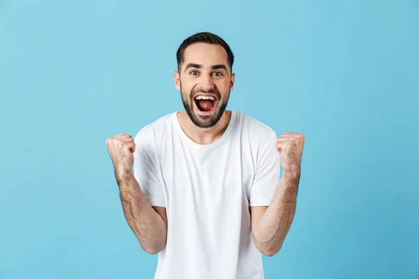 Молодий кричущий щасливий бородатий чоловік позує ізольовано на синьому фоні стіни робить жест переможця . — стокове фото