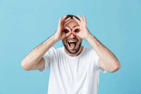 Emocionado hombre barbudo feliz posando aislado sobre fondo de pared azul mostrando gestos de gafas con las manos divirtiéndose . —  Fotos de Stock