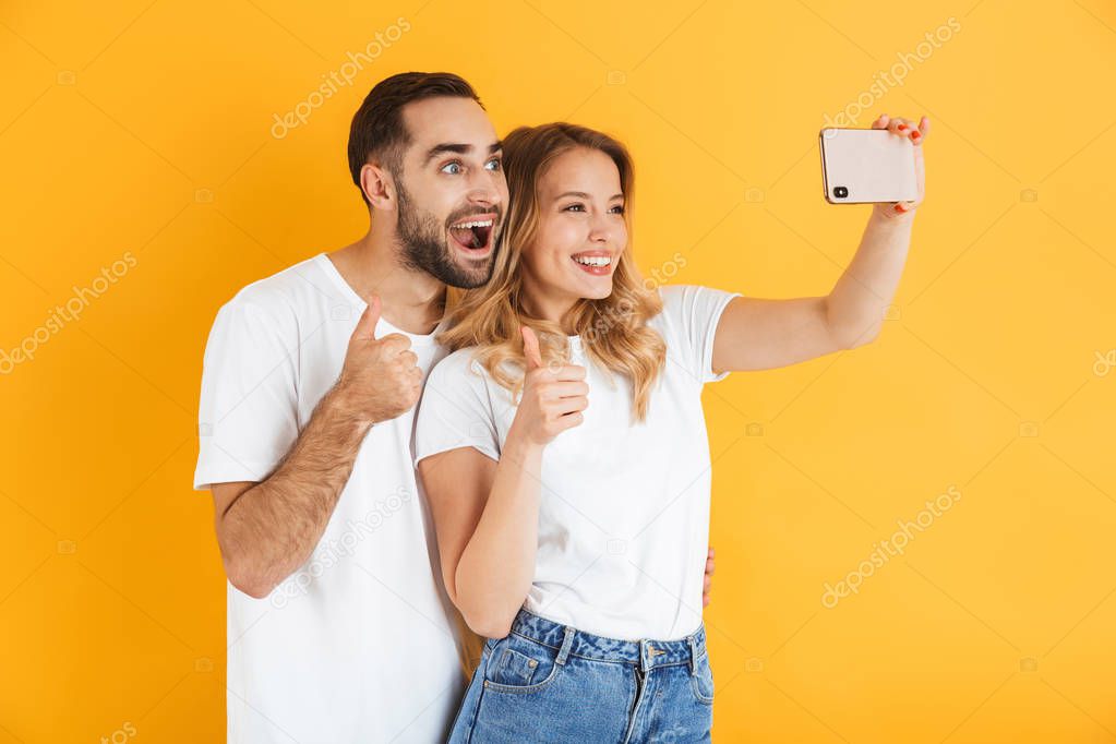 Excited cheerful young couple standing isolated