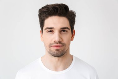 Ciddi konsantre genç adam beyaz duvar arka plan üzerinde izole poz.