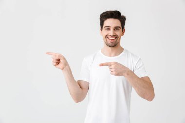 Heyecanlı genç adam beyaz duvar arka plan işaret üzerinde izole poz.