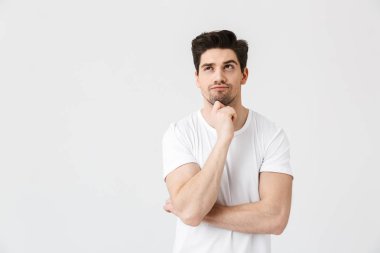 Konsantre genç adam beyaz duvar arka plan üzerinde izole poz.