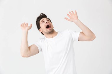 Çığlık lar, beyaz duvar arka planı nın üzerinde izole poz veren genç adam tarafından korkutuldu.