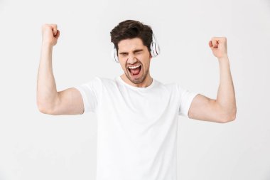 Duygusal heyecanlı genç adam kulaklık ile müzik dinleme beyaz duvar arka plan üzerinde izole poz.