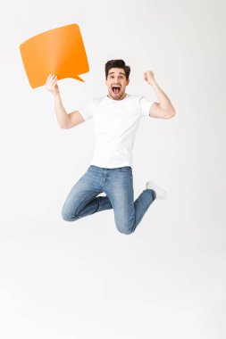 Duygusal heyecanlı genç adam konuşma balonu tutan beyaz duvar arka plan üzerinde izole poz.