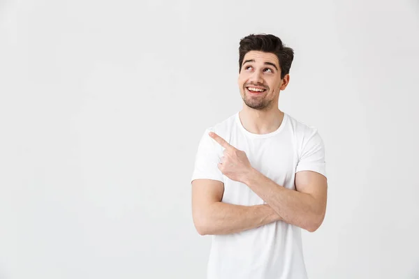Jeune homme excité posant isolé sur fond de mur blanc pointant . — Photo