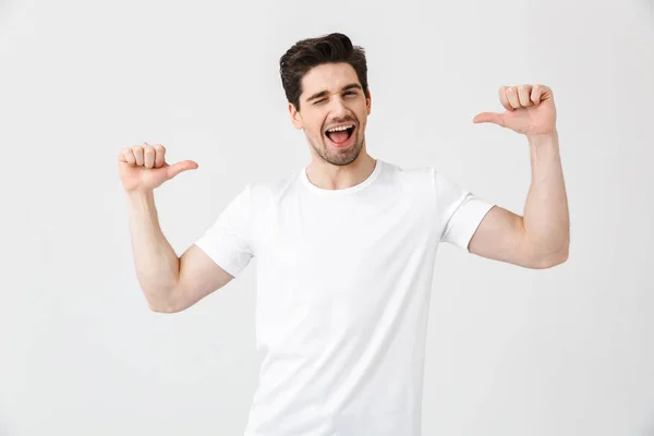 Emocionado joven posando aislado sobre fondo blanco de la pared apuntando . — Foto de Stock