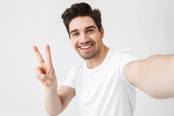 Animado feliz jovem posando isolado sobre branco parede fundo fazer um selfie por câmera . — Fotografia de Stock