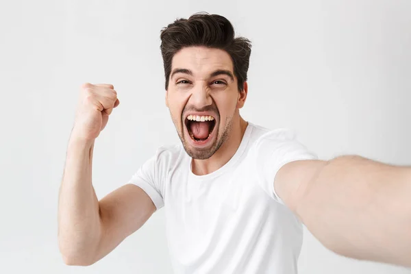 Emocionado joven feliz posando aislado sobre fondo blanco de la pared hacer un selfie por la cámara . — Foto de Stock