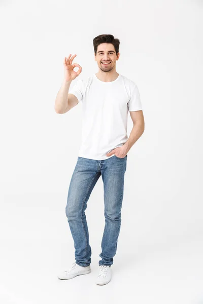 Feliz animado jovem posando isolado sobre fundo da parede branca mostrando gesto ok . — Fotografia de Stock