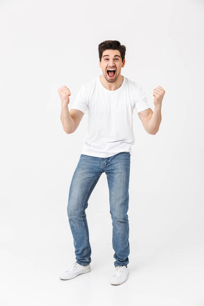 Excited happy young man posing isolated over white wall background.