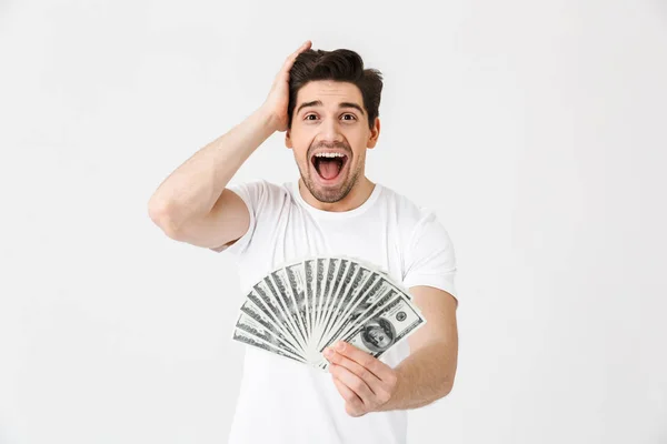 Schockiert aufgeregt glücklich junger Mann posiert isoliert über weiße Wand Hintergrund hält Geld. — Stockfoto
